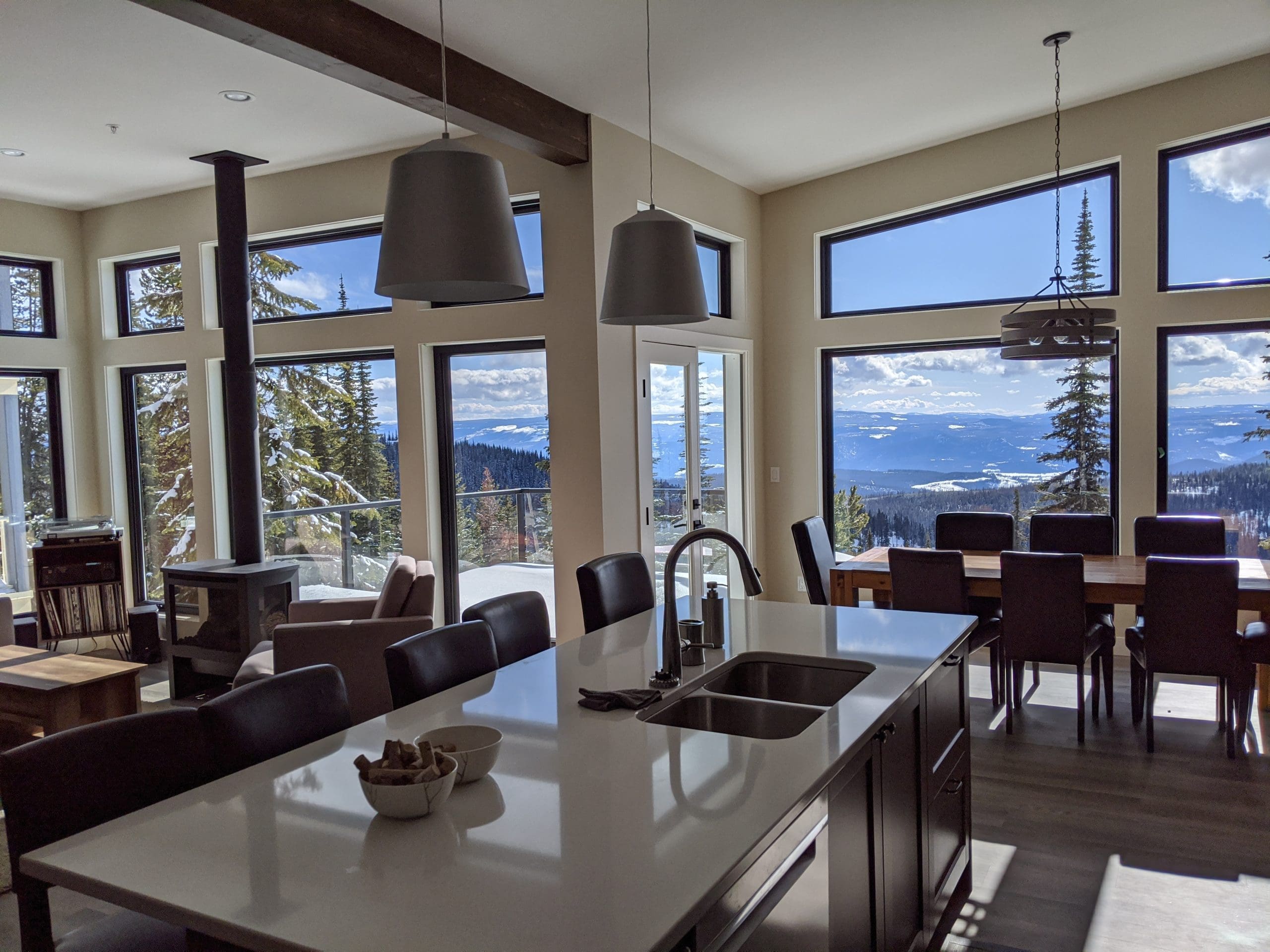 Living Room/Kitchen and Dining table with large bright windows with mountain views, fully equipped kitchen, private hot tub, laundry, lower level den/TV room.