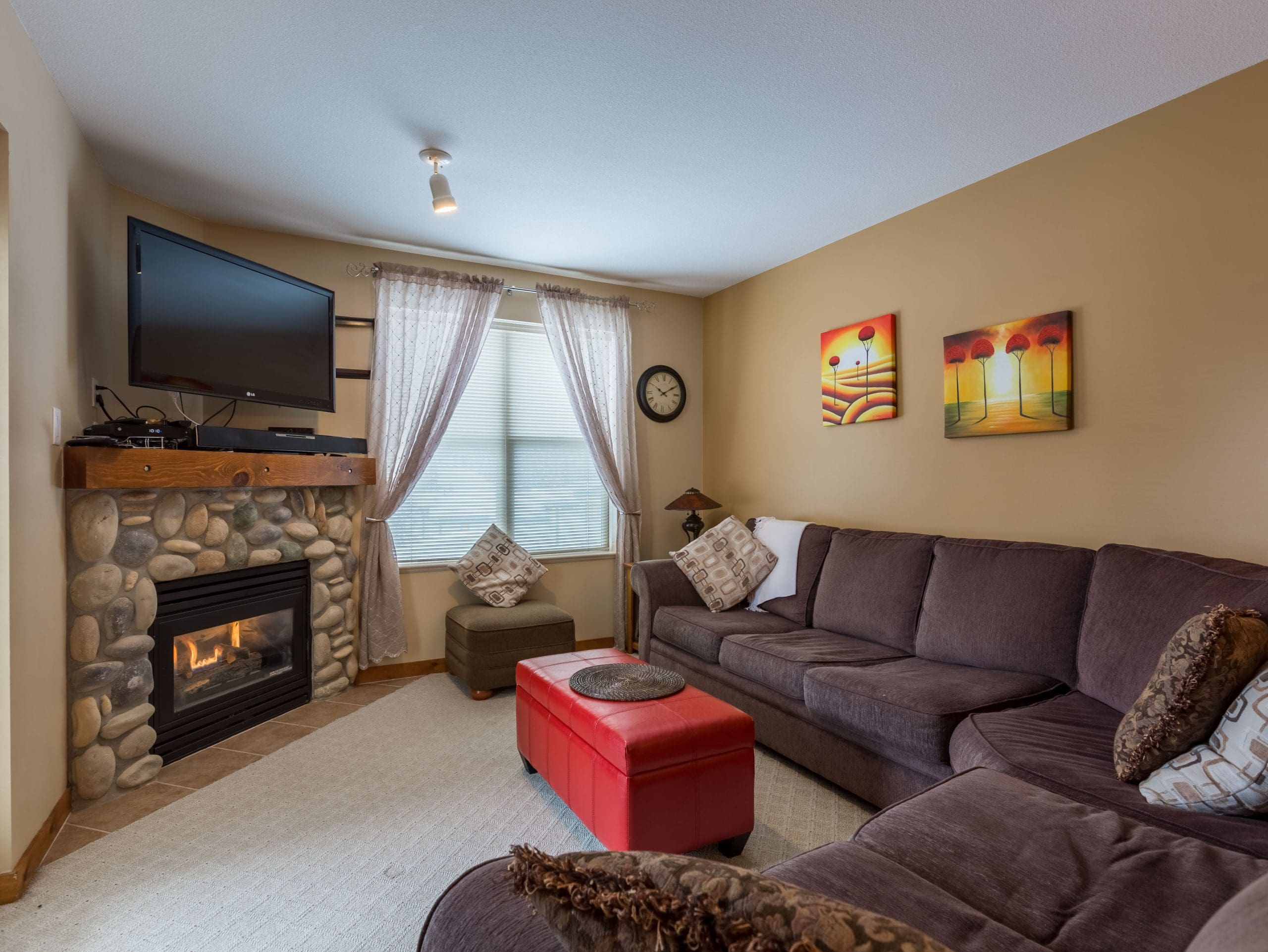 Living room of corner 2 bedroom condo. Gas fireplace, TV, large balcony with private BBQ. Pet-friendly too!