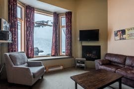 Living room with bright open windows, gas fireplace, TV. Private deck with BBQ, hot tub with mountain views. Ski right to and from your door, and only steps away from the village. Pet-friendly too!