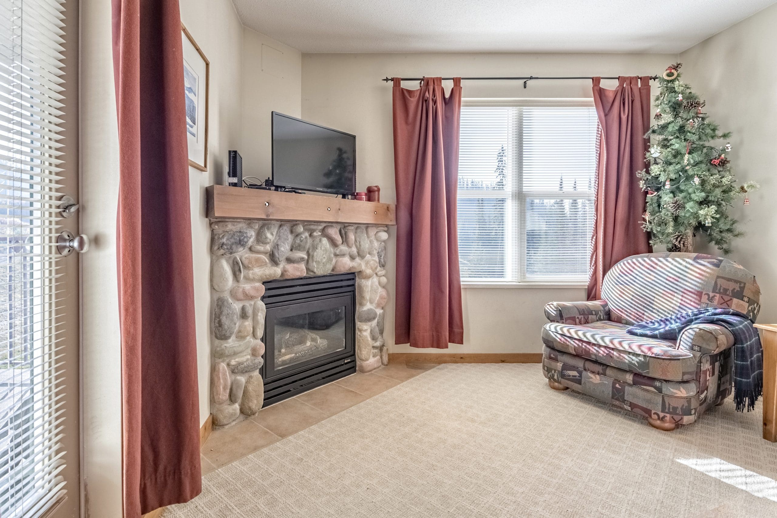 Living room with gas fireplace, bright open windows with views of the Silver Queen chair and Tube Town. Top floor condo with balcony, TV, free parking. It's pet-friendly too!