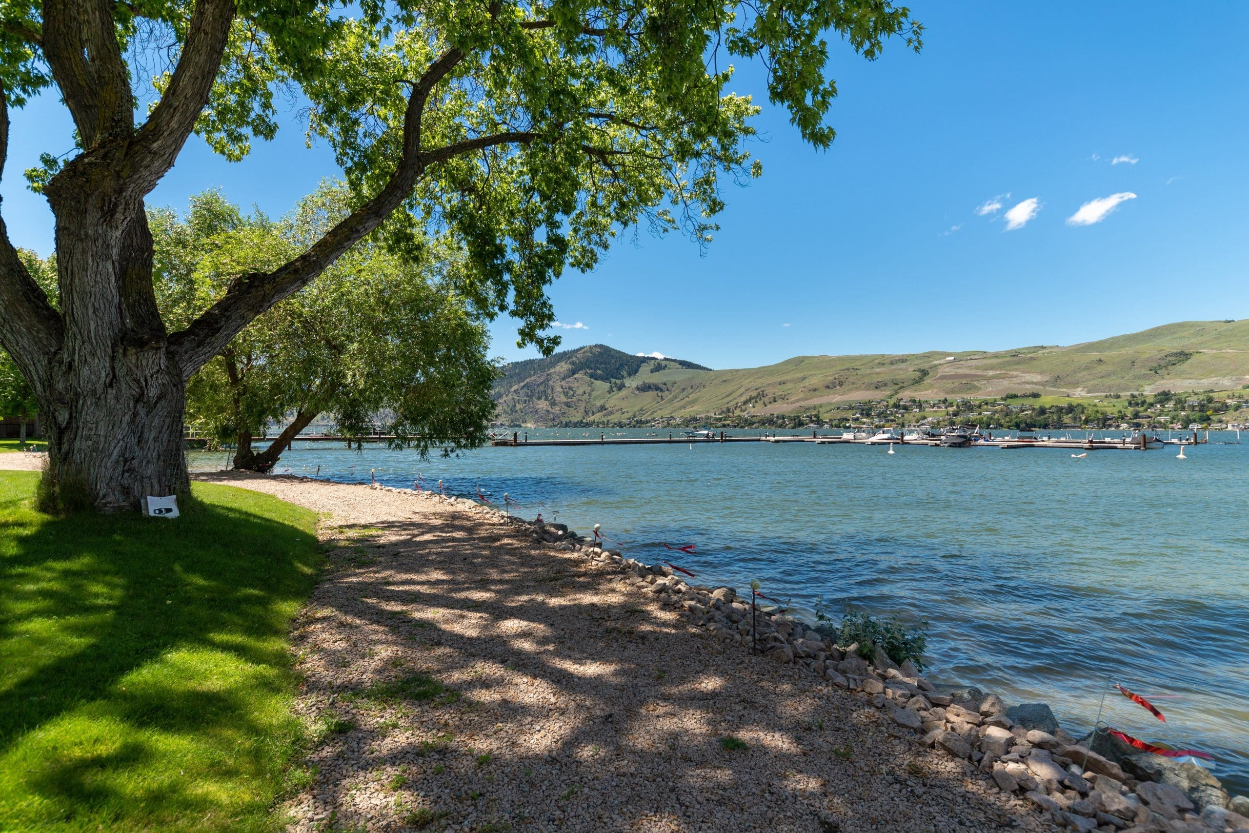 Photo of Okanagan Lake and private beach for guests of this condo. Ground floor condo at The Strand in Vernon with access to outdoor pool, hot tub, courtyard with fire pit, and private beach area. Relax by the lake for your summer vacation with a small family or couples trip.