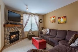 Living room of corner 2 bedroom condo. Gas fireplace, TV, large balcony with private BBQ. Pet-friendly too!
