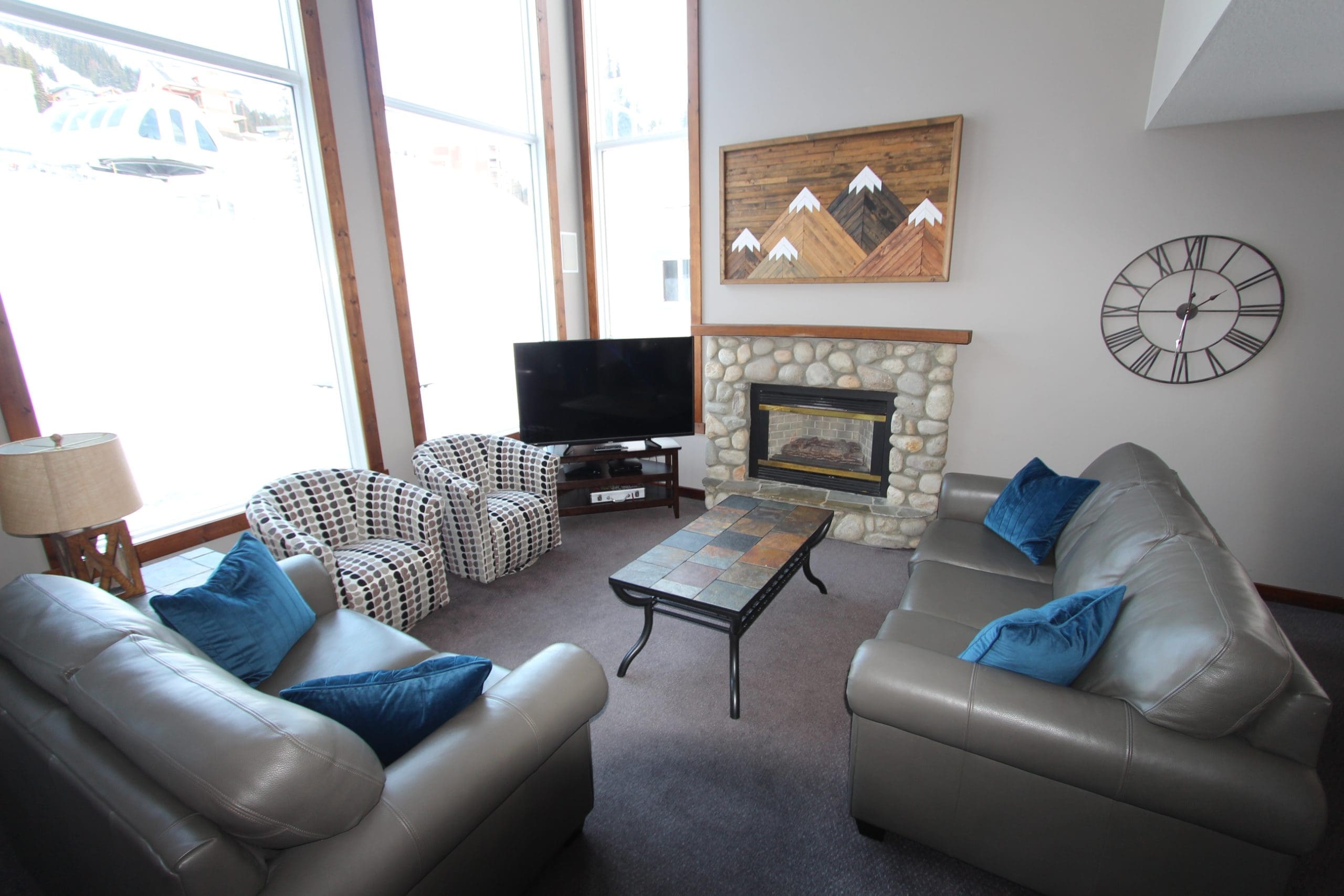 Living room of Ridgeview Upper. Beautiful tall bright windows with views of the Alpine meadows chairlift behind the home. Incredible ski in and ski out right from your backyard to the chairlift, and a quick walk to the village. Private hot tub, laundry, heated boot and gear room, multiple areas of living space for family/friends and natural gas BBQ.