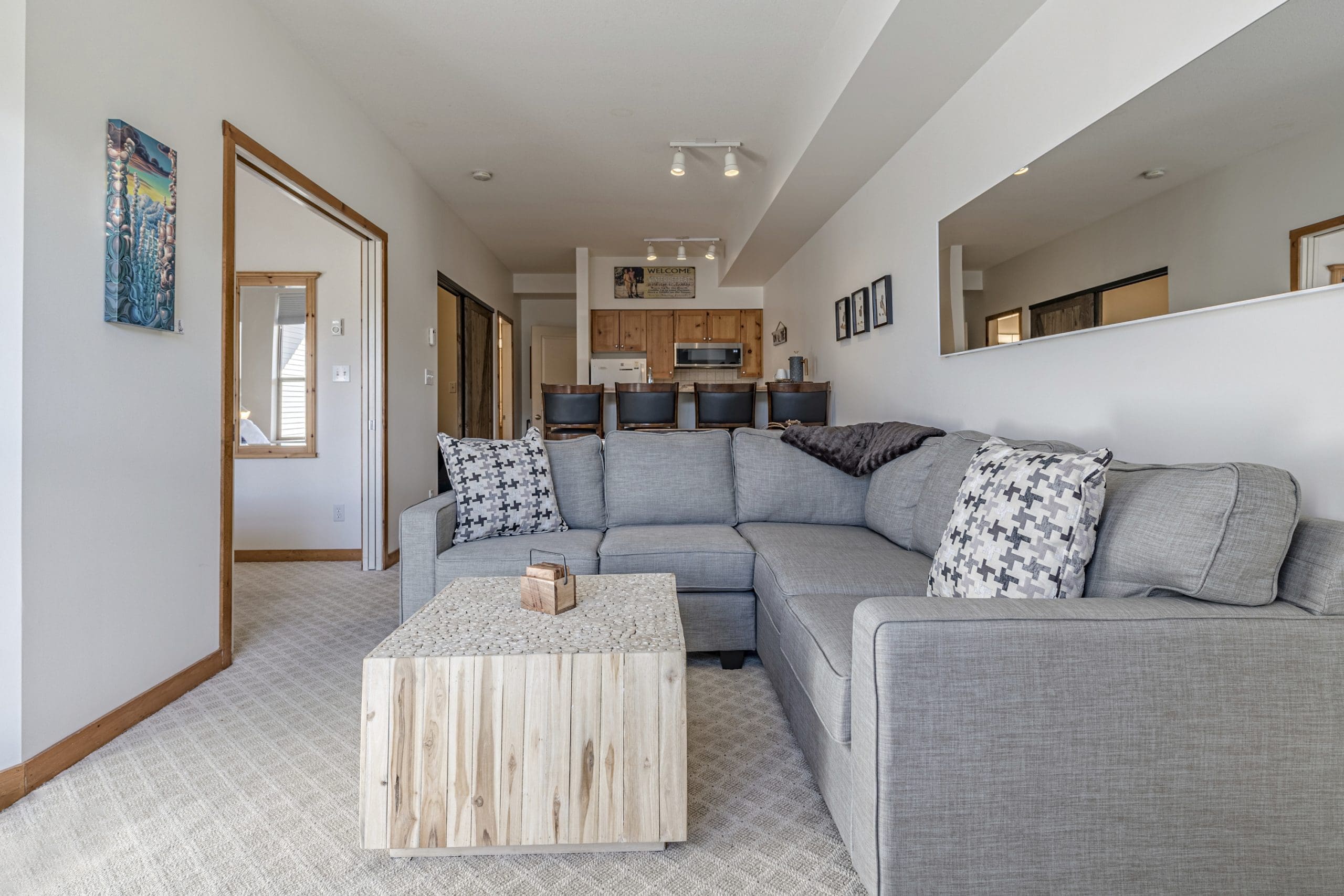 Living room of ground floor condo. Pet-friendly, modern and open concept living, fully equipped kitchen, BBQ on deck, and ski storage at front of unit. Start your day right on the hill!