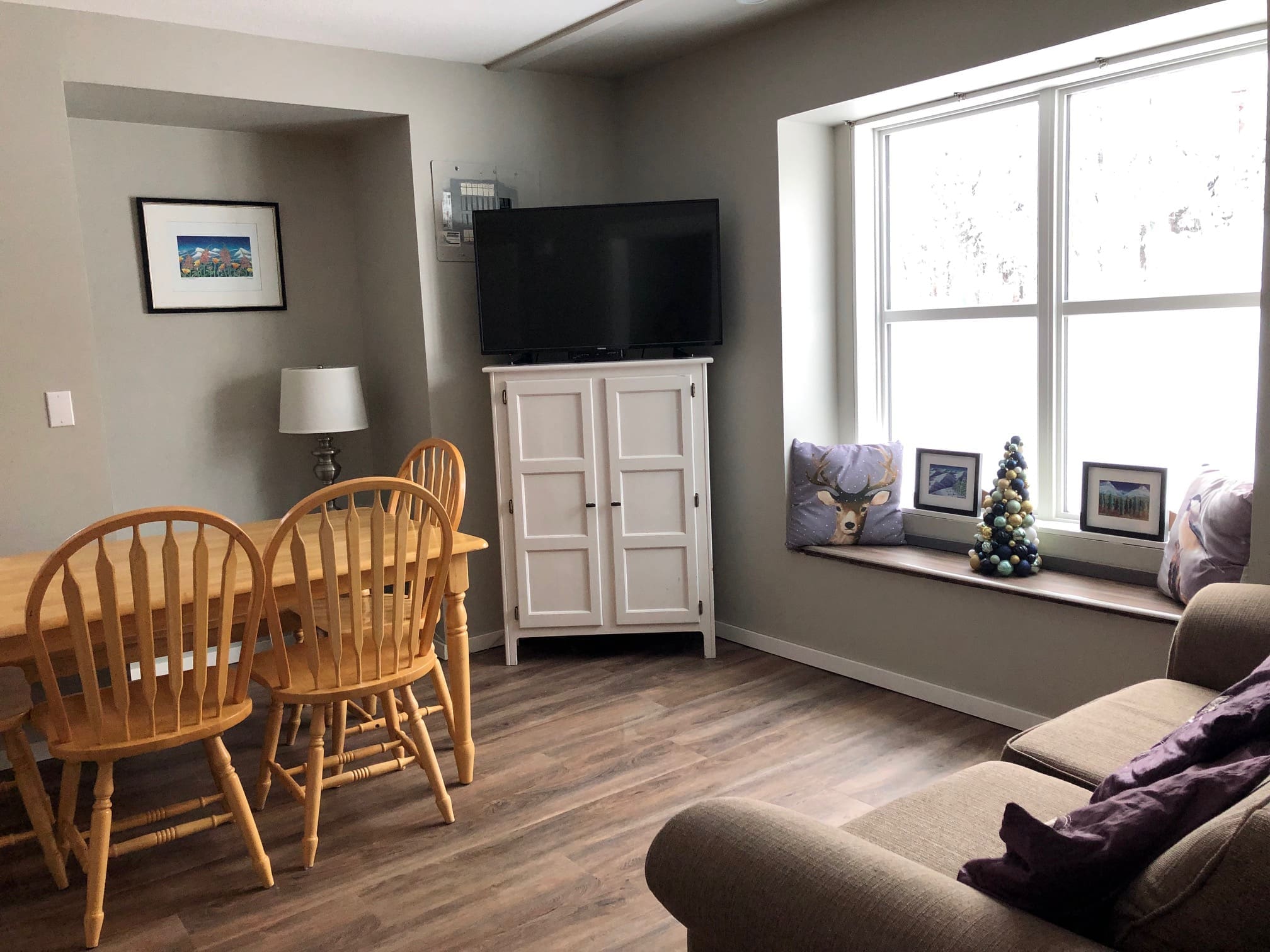Living room with dining table, fireplace and TV. Cozy one bedroom ground floor suite with great access to the skiway and trails to start your day. Pet-friendly, brand new BBQ and semi-private hot tub.
