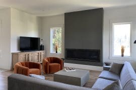 High-end modern living room with gas fireplace and bright natural light from the windows.